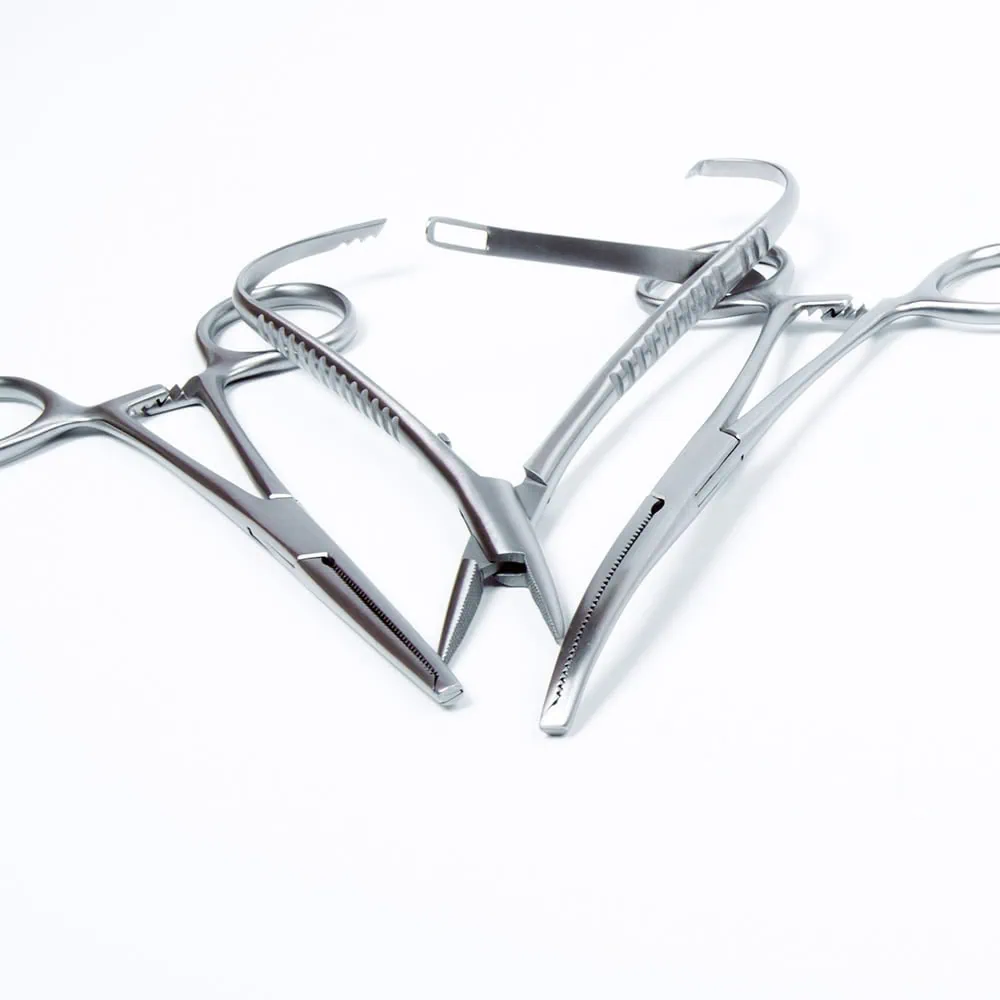 Several metal surgical instruments on a white surface, including clamps and forceps.