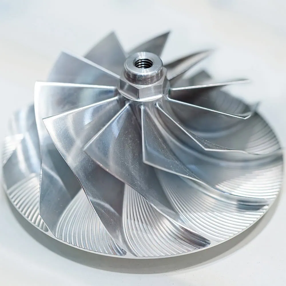 Metallic turbine wheel with sharp edges and a central thread.