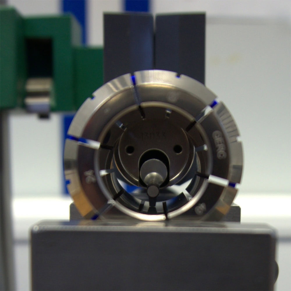 Close-up of a FAHRION clamping system holding a cylindrical workpiece. It shows precise details of the collet in a technical environment.