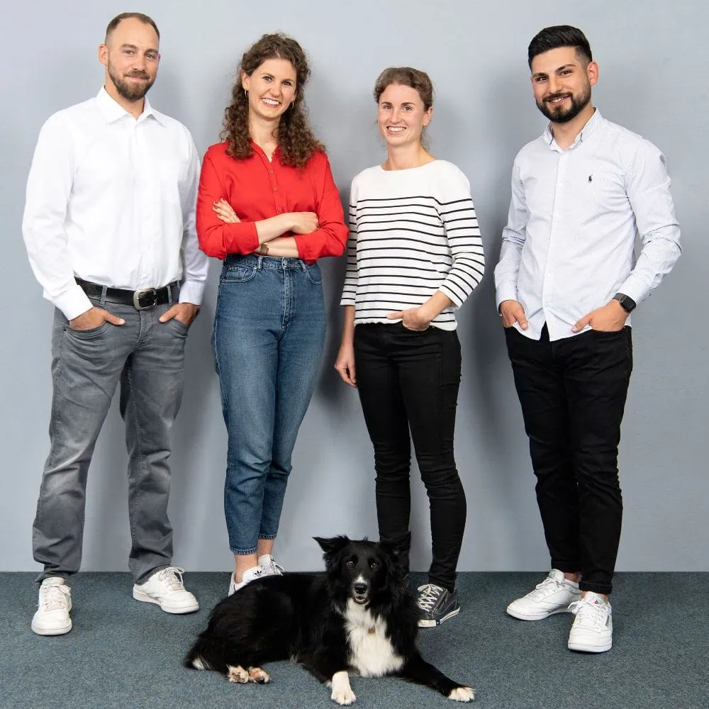 Vier Personen und ein Hund stehen zusammen.